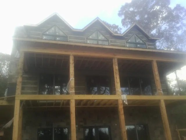 Dormers and porch framing on a large log home under construction — Roof Coating work by our crew in Cleveland